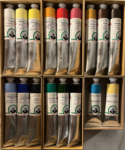 6 small boxes containing Old Holland oil paints. From left to right & top to bottom Titanium White, Nickel Titanium Yellow, Scheveningen Yellow Lemon, Indian Yellow-Orange Lake Extra, Scheveningen Red Light, Ultramarine Red-Pink, Yellow Ochre, Red Umber, Burnt Umber, King’s Blue Light, Ultramarine Blue Deep, Indigo, Emerald Green, Sapgreen Lake Extra, Scheveningen Black, and two smaller tubes: Genuine Manganese Blue, Genuine Naples Yellow