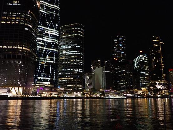 Skyscrapers lit at night and reflected in the dark river waters below
