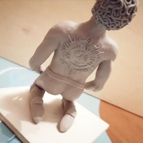 Die Rückseite meiner Figur vom Vampir Astarion aus Baldurs Gate 3. Er kniet, trägt nur eine Hose und man sieht die Narben auf seinem Rücken die sein Herr Cazador verursacht hat. Es sind drei Ringe die mit infernalen Buchstaben versehen sind und den kompletten Rücken einnehmen.
