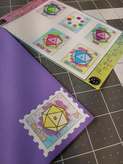 A picture of some custom designed stamp stickers foe Diceawaii. Im the background, a colorful sheet of stickers shaped like stamps, missing 1 of the 6

In the foreground, the 6th sticker is stuck to a purple envelope like a stamp. It depicts a yellow d20 with a 19 and the words 'so close'