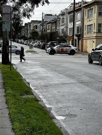 A Waymo AV stopped for a red light off cameral left in the middle of the intersection of the street prior to the light.