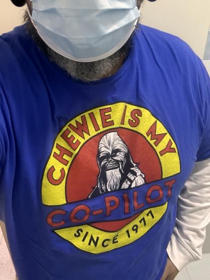 Person wearing a blue t-shirt with a graphic stating "CHEWIE IS MY CO-PILOT SINCE 1977" featuring an image of Chewbacca from Star Wars. The person is also wearing a surgical mask.
