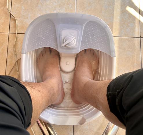 A person's feet soaking in a foot spa bath.