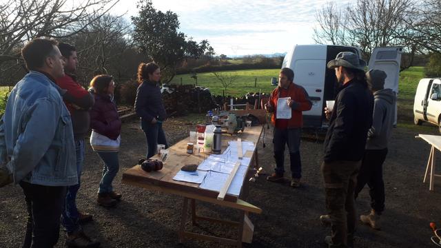 Début de la formation, notre groupe est concentré et écoute attentivement notre formateur nous expliquer le déroulé de la formation, nous présenter les outils et la démarche.
Dans une cours de ferme avec prairie et bois à l'arrière plan.