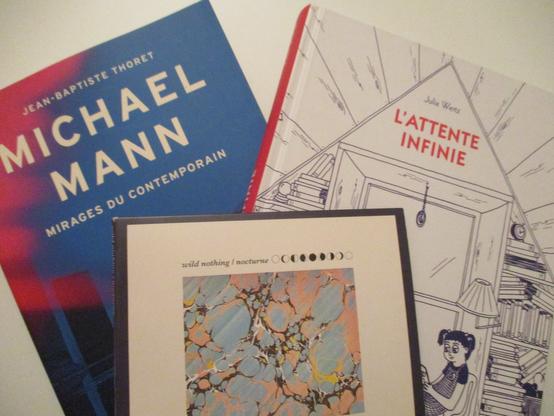 Livre à gauche à la couverture rose bleue de Jean-Baptiste Thoret, Michael Mann : mirages du contemporain ; la BD L'Attente infinie de Julia Wertz à droite, représentant une alcôve de son enfance ; au 1er plan, l'album du groupe US Wild Nothing Nocturne à la peinture abstraite bleutée et orangée