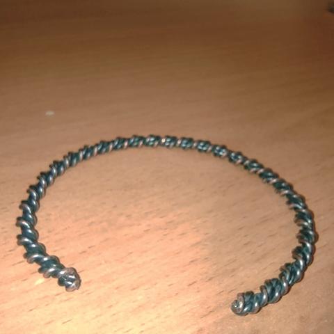 Twisted copper wire has been treated with patina and bent into a bangle.