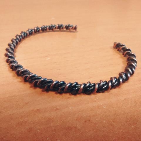 The bangle lies fairly flatly on a wooden surface