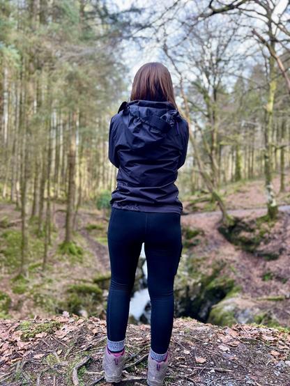 A girl talking a photo of a bridge across a ravine in the woods