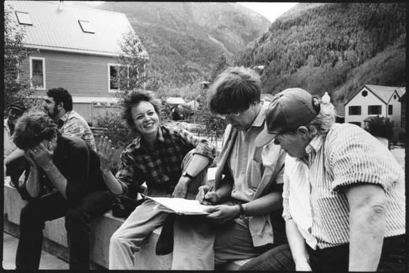 A black-and-white photo of composers (left to right) I Wayan Sadra, Larry Polansky, Jim Tenney (head in hands), Laurie Anderson, Roger Reynolds, and Pauline Oliveros sitting outside, struggling with the wording of their manifesto on censorship.