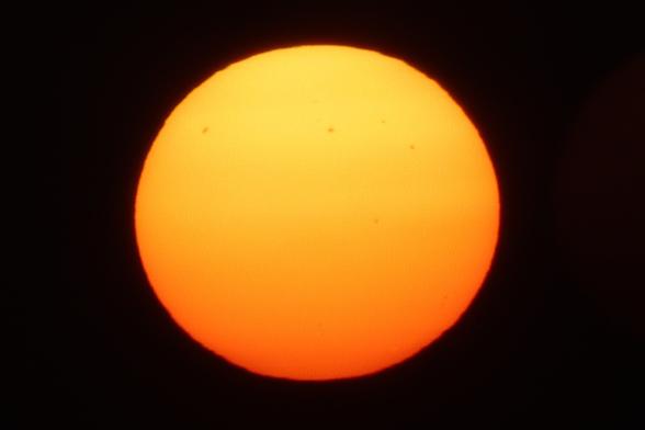 A photo taken directly into the Sun, showing its sunspots. At least 5 larger clusters of spots are clearly visible, and there's a couple more fainter, smaller ones visible to a keen eye, too.