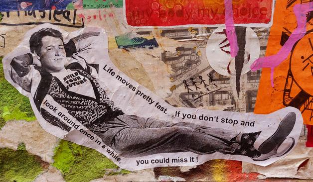 Kunterbunt beklebte Wand. In der Mitte ein schwarz-weißer Aufkleber, der einen jungen Mann im 50er-Jahre-Freizeit-Style zeigt. Er liegt bequem nach hinten angelehnt, lächelt, die Arme hinterm Kopf verschränkt, die Beine lässig übereinander geschlagen. Um ihn herum steht: "Live moves pretty fast. If you don't stop and look around once in a while, you could miss it."
Auf seinem Shirt steht: BUILD YOUR FUTURE.