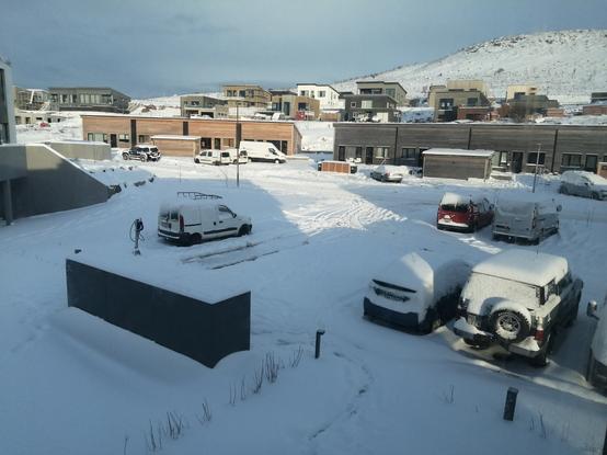 Le soleil inondé l'appartement et le parking de l'immeuble. Le toit des voitures possèdent une épaisse couche de neige.