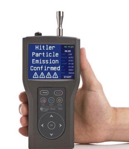 Picture of Human hand holding up a radiation meter, with a digital screen showing the words “Hitler Particle Emission Confirmed” followed by four alert symbols
