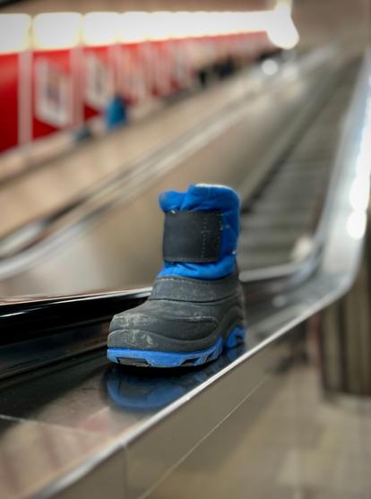 Ein verlorener Kinderschuh steht an einer Rolltreppe