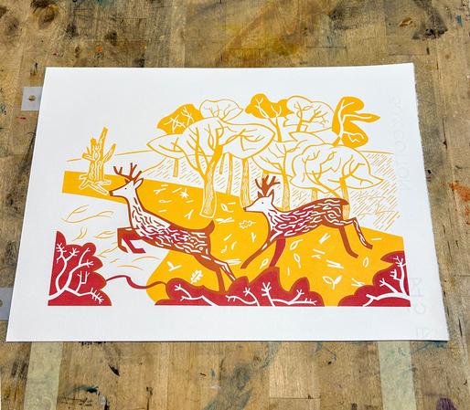 A two colour screenprint of two stags leaping. The stags are in red and the background is in a golden yellow.
