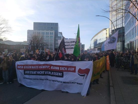 Foto des Antikapitalistischen Blocks in der Menschenmasse mit dem Front-Transpi "Wer gegen Nazis kämpft, kann sich auf den Staat nicht verlassen. Repressionen stoppen - Freiheit für alle inhaftierten Antifaschist*innen"

Dahinter einige Antifa-Fahnen und viele Aktivisti.