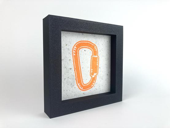 A framed relief print of a carabiner.