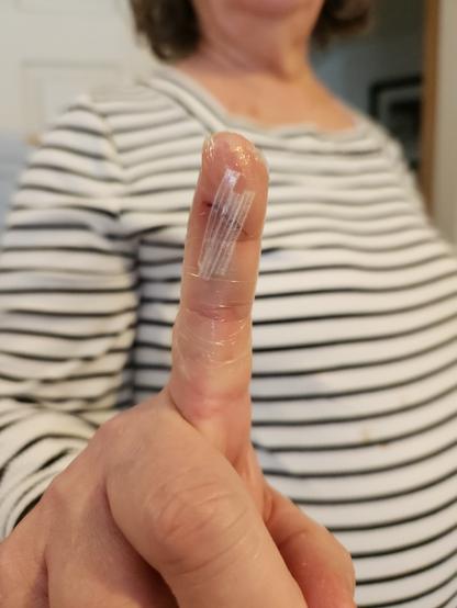 My wife holding up her cut index finger to display my bandaging efforts.