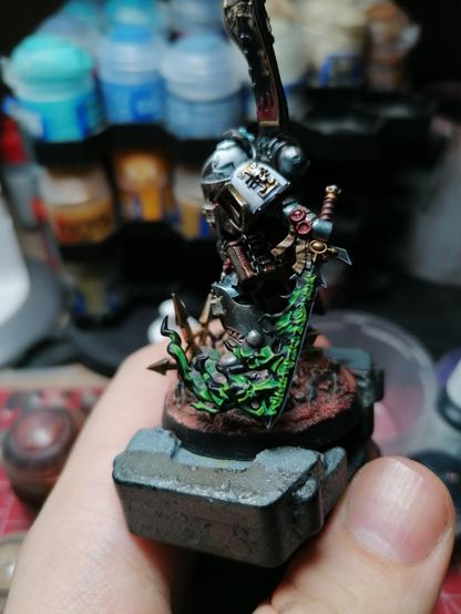 A space marine in metallic Grey armor, we can see his sword wich is black with green runes and fumes