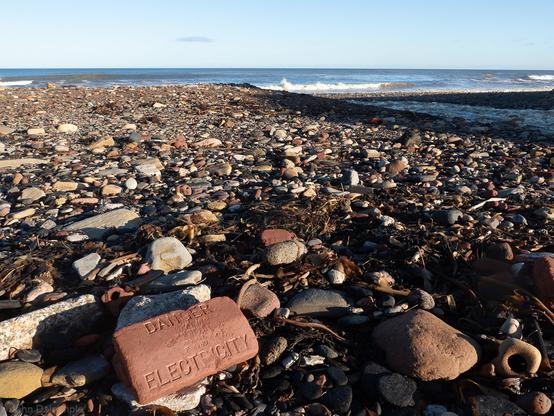 Industrial rubble washed out and dumped at the mouth of a stream as it reaches the sea.