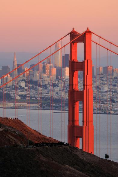 North tower of the Golden Gate Bridge; San Francisco in the background; sunset light.