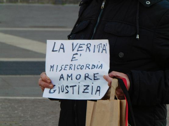 a person holding a sign reading:   "LA VERITÀ È MISERICORDIA, AMORE, GIUSTIZIA"  (italian for  'Truth is Mercy, Love, Justice') .    these pictures were taken at a demonstration   held in Rome  for Emanuela Orlandi's birthday  , organized by her brother Pietro ;     Emanuela would have been 56 now ,   but she went missing in Vatican city in June 1983  when she was just 15 .     this is a very interesting and complex  unsolved case,  i recommend you to research about it
