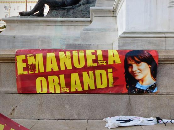 another banner  using another different picture of Emanuela Orlandi  smiling, on the right,    and her name  on the left ,  in yellow capital letters   on red background