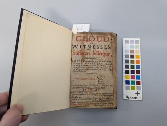 A book with the left board held open. Left endleaf cream machine made paper. 
Title page on right: A cloud of witnesses; or, The sufferers mirrour. Discolouration at edges. Staining in centre.