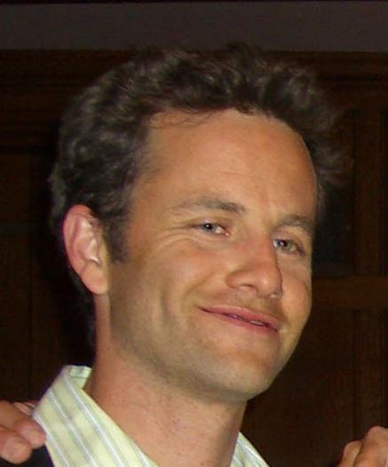 A headshot photo of Kirk Cameron. His is smiling with his lips slightly parted. The smile appears asymmetrical, indicative of a smirk.