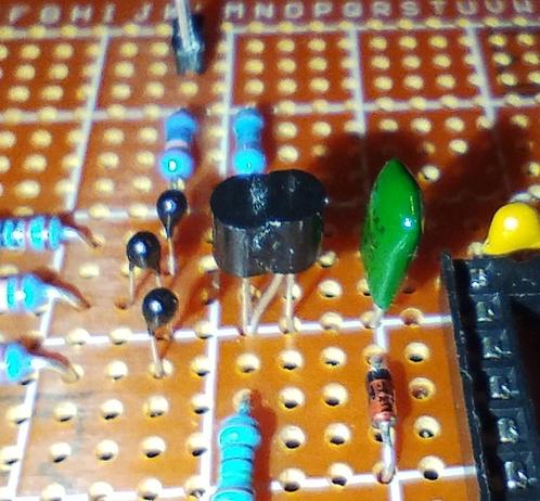 two superglued transistors in the middle of a couple of components. they look like dancing, especially since the right one's middle leg is stretched into the hole of the side leg of the other one