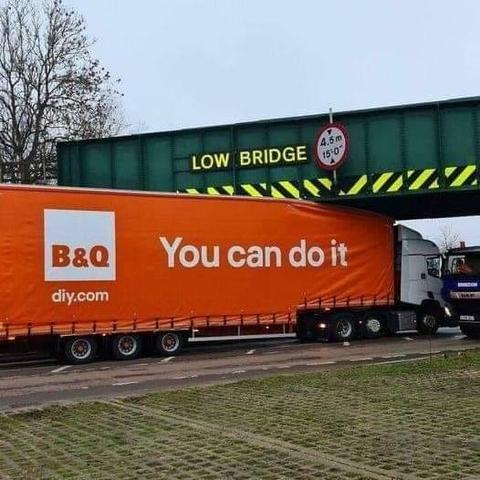 giant orange B&Q (diy.com) truck with the slogan "You can do it" that has jammed itself under a low bridge.
