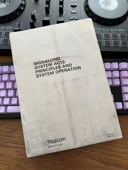 A4 document with a white cover, text reads:

Signalling system AC13 principles and system operation
British Telecom, BTHQ/IT 7.2.2C, issue 1, Jan 83

In the document number I believe “BTHQ/IT” = British Telecom HeadQuarters, Internal Training