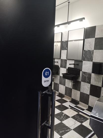 Entrance to a public toilet facility with a sign "£1 ENTRY"