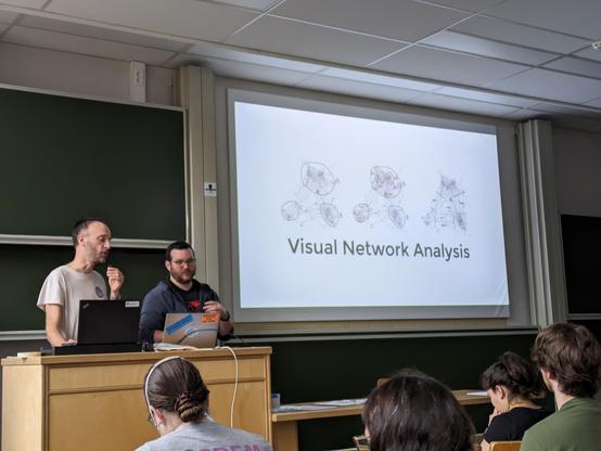 Paul and Alexis in front of a slide reading "Visual Network Analysis".