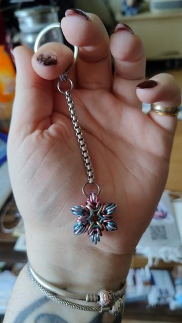 le porte-clefs en forme de rosace à 6 branches et aux couleurs trans, bleu, rose et blanc