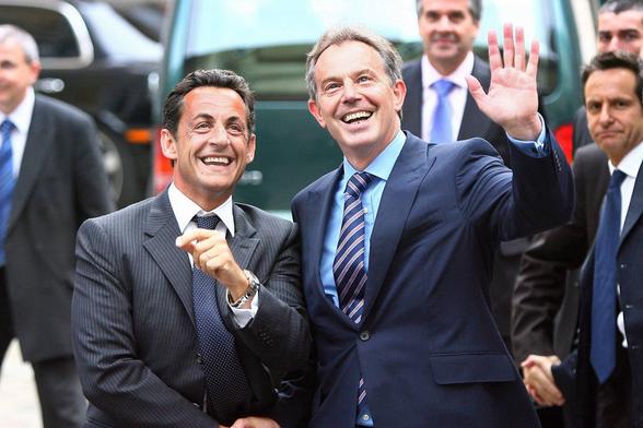 Sarkozy and Blair in suits shake hands and smile