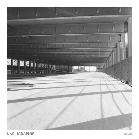 Ein Parkhaus am Sonntag. Platzverschwendung zumindest auf 14 Etagen übereinander. Der Schnee reicht auf die Parkfläche und der Schatten des Metallgerippes zeichnet am Boden seine Linien. Ein Liminal, sozusagen.