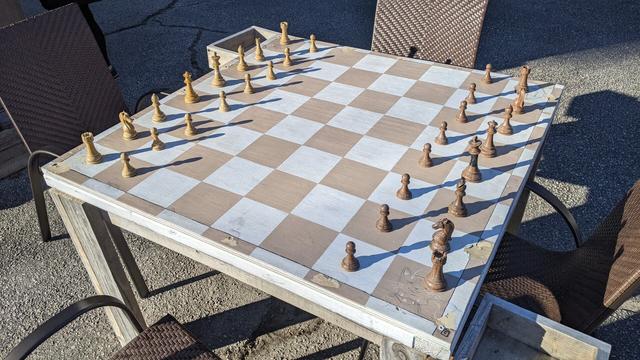 A table that is a large chess board with pieces on it.