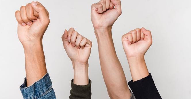 Image of four forearms raised in the air with clenched fists.