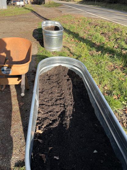 Two water troughs filled with soil and parsnips seed
