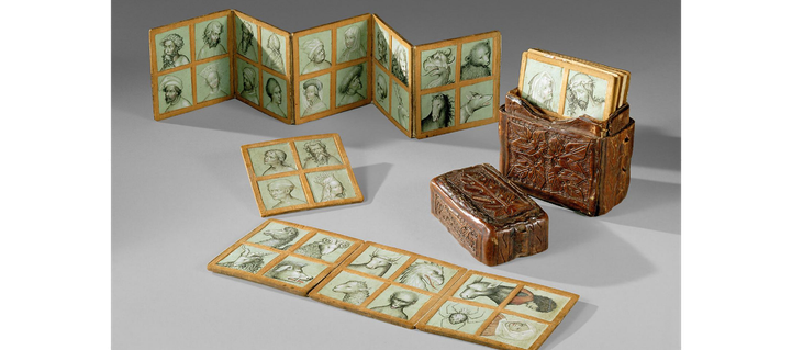 Vue d'ensemble : une boite e cuir bouilli dans laquelle sont ragée des "fiches" carrées apparemment cartonnées soit libres, soit multiples et pliées en accordéon, chacune portant 4 dessins à la plume : portrait de types physiques -jeune fille, vieux barbu, christ etc - mais aussi d'animaux