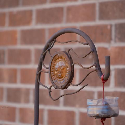 Garden hanger with a glass sun, in front of a brick wall