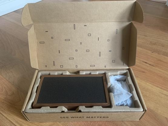 Lifting the foam reveals a miniature LED display with a beautiful wooden frame, and a power adapter wrapped in plastic.