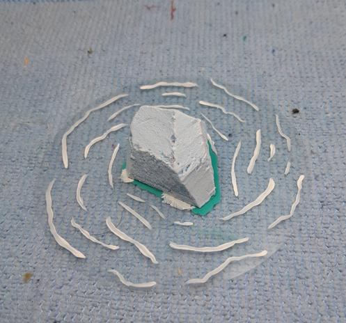 an iceberg for a wargame, carved and painted foam on a clear circle of plastic with drawn waves.