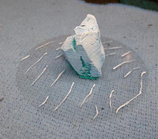 Icerberg for wargaming made of carved foam glued to a clear circle of plastic with painted waves.