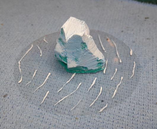 Icerberg for wargaming made of carved foam glued to a clear circle of plastic with painted waves.