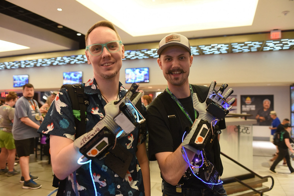 Two happy DEF CON attendees wearing PowerGloves upgraded by some Flipper Zeros.