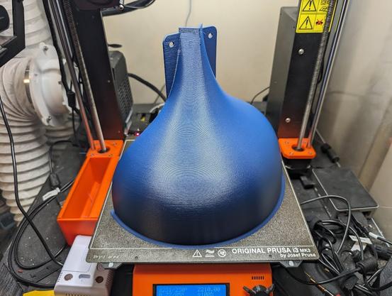 A squirrel baffle being printed by a 3d printer, as seen from the other side.