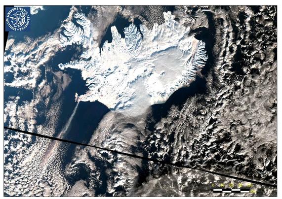 Vue satellite de l'Islande qui est entièrement couverte de neige. On aperçoit en bas à gauche le filet de fumée de l'éruption qui se diriger vers le sud-ouest.