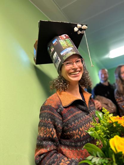 A smiling Meike Schickhoff wearing her PhD hat after the defense.